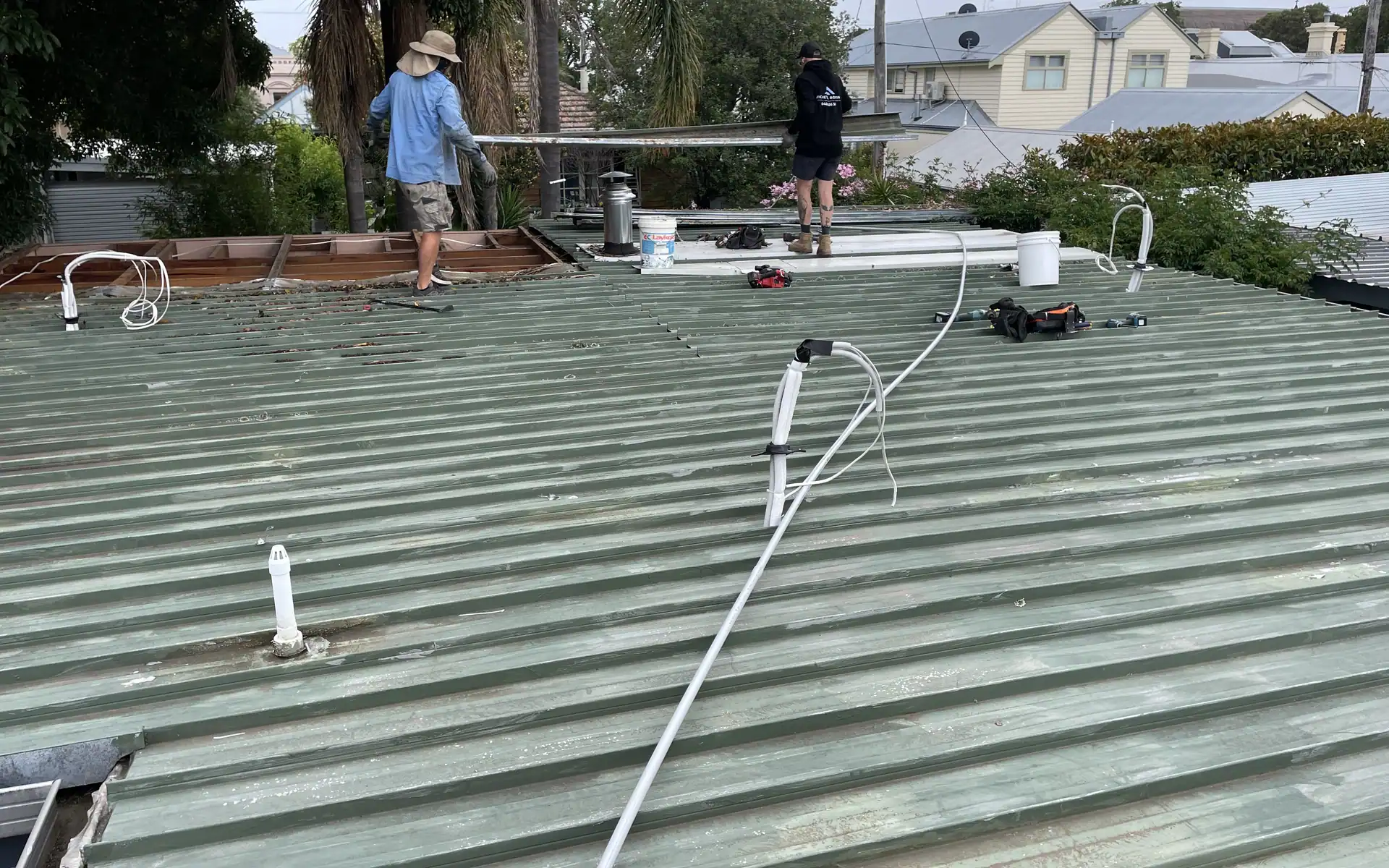 Roofers working on an old corrugated roof being stripped