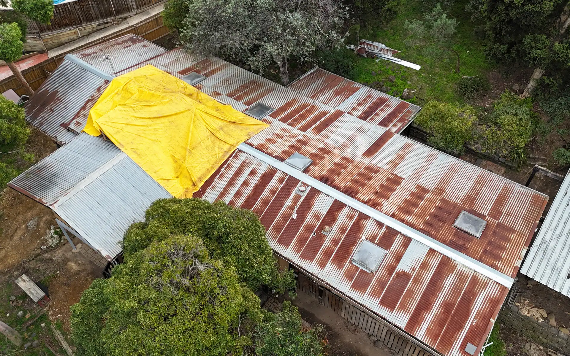 Rusted roof with a tarpaulin over a leak